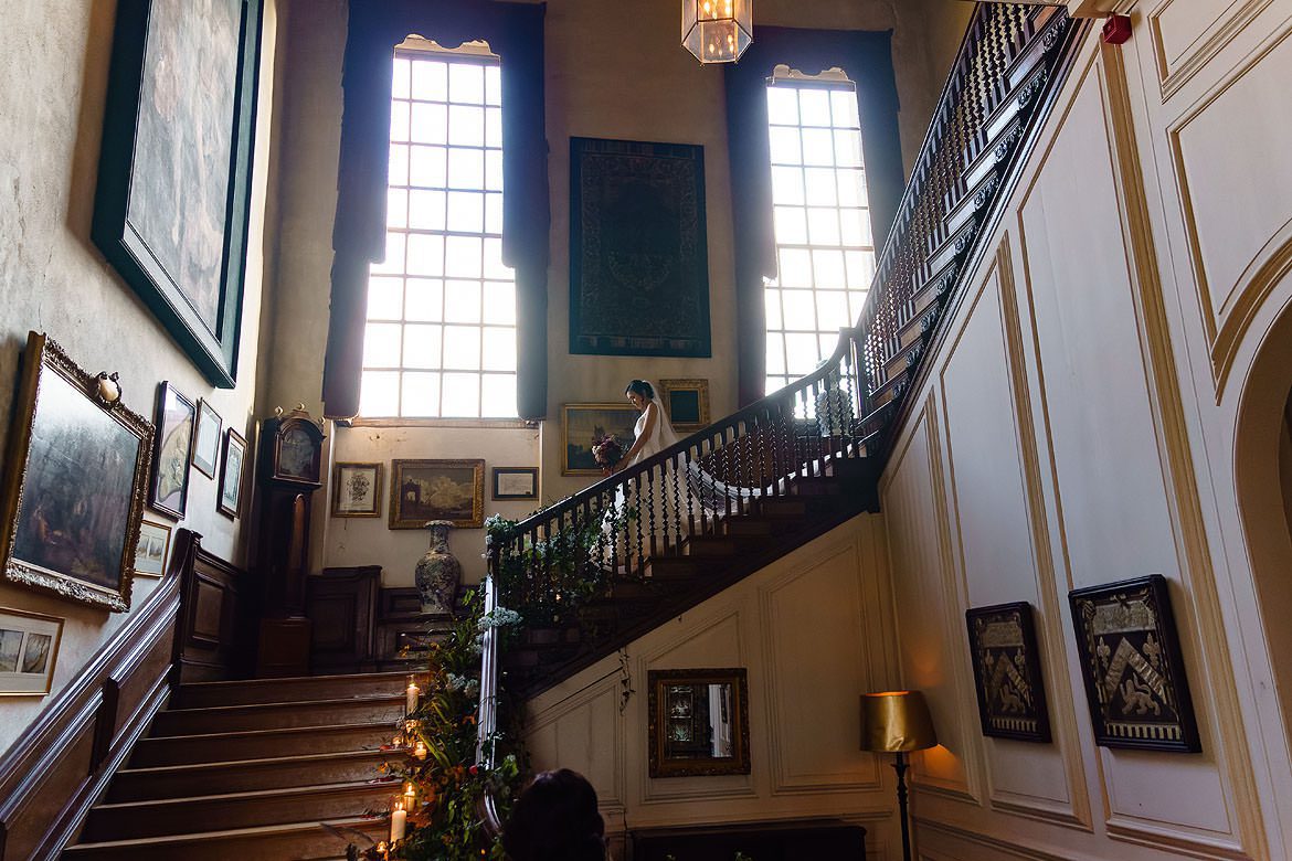 Bride walking down the grand staircase at Glemham Hall